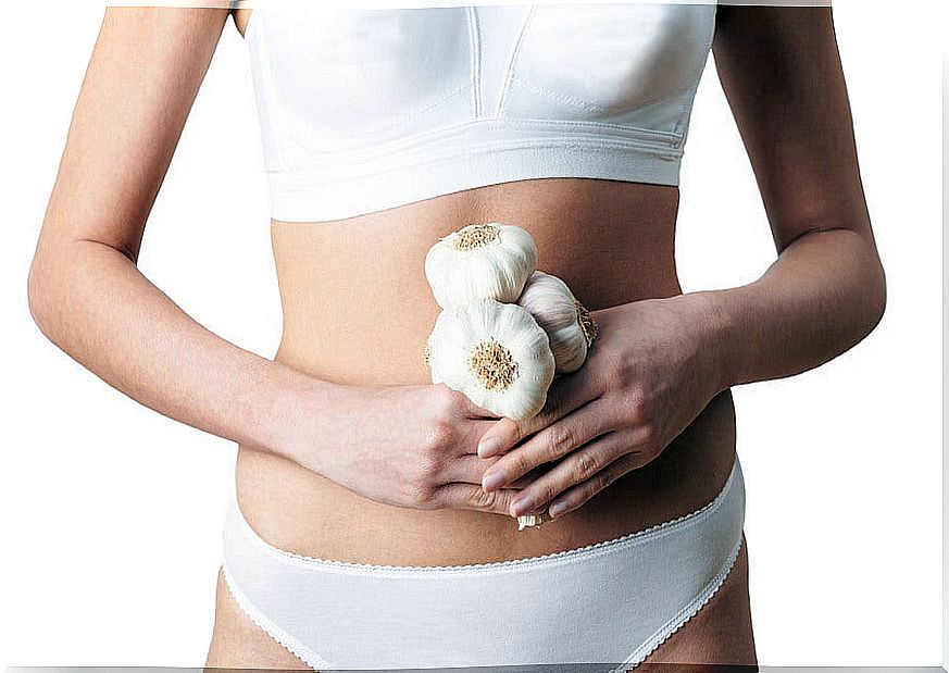 Woman holding several heads of garlic.