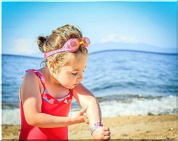 Girl looking at her skin on the beach